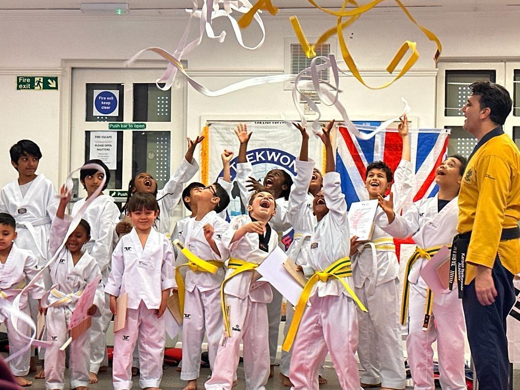 taekwondo classes london Excited Taekwondo students celebrate with their instructor, tossing ribbons in the air.